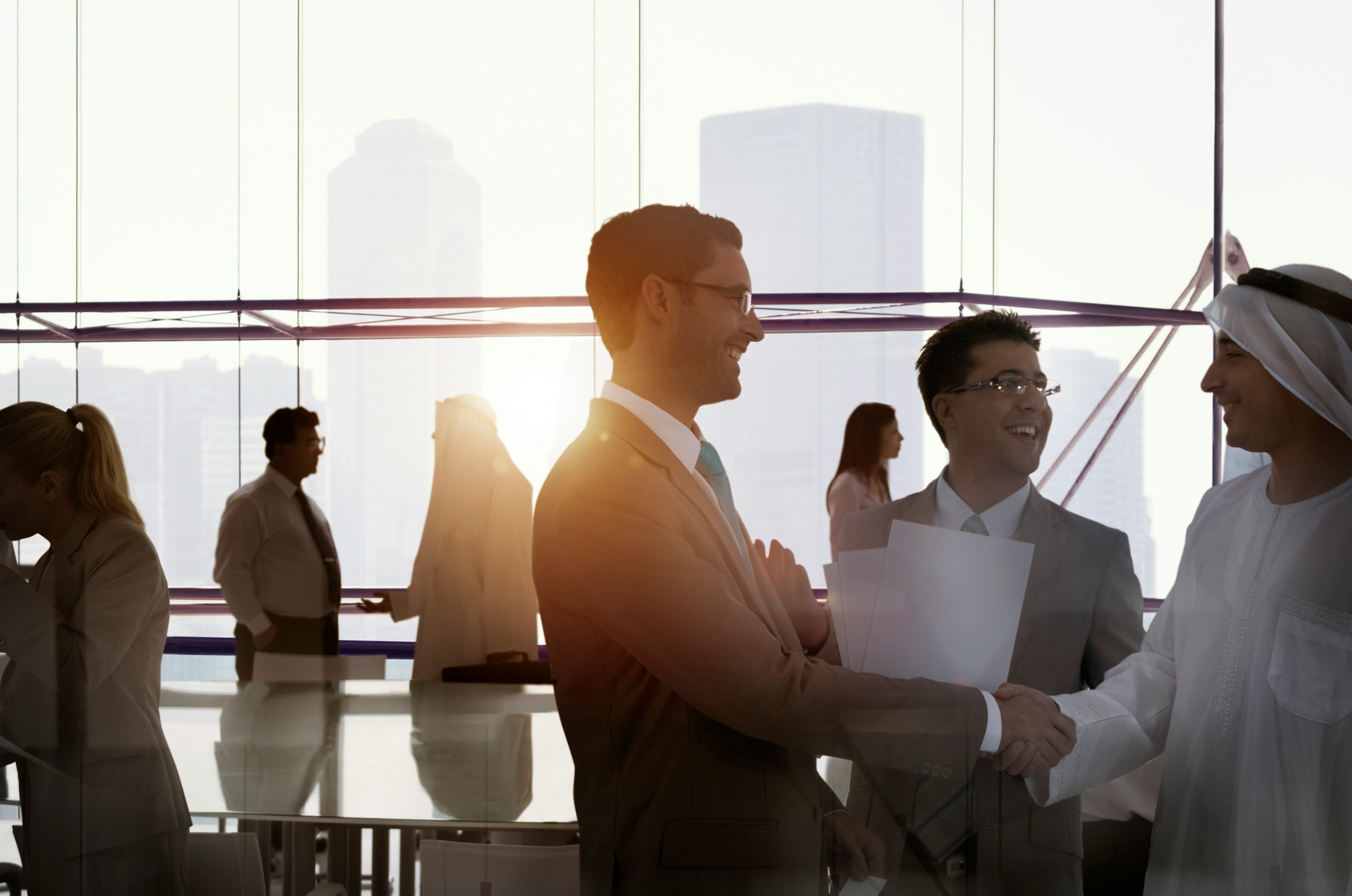 Business partners shaking hands in a sunlit office overlooking the city skyline